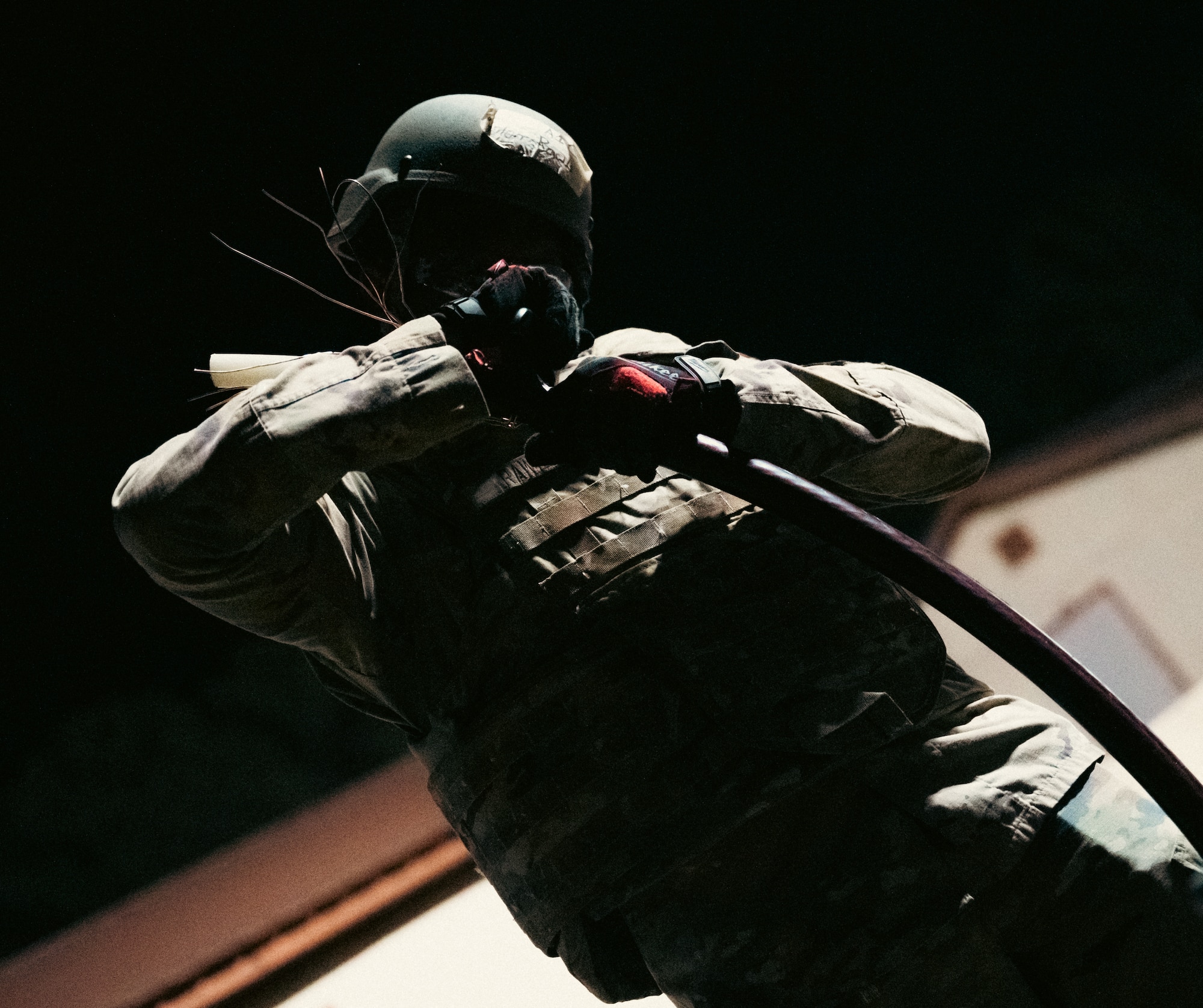 A male airman holds a splice at an angle at night