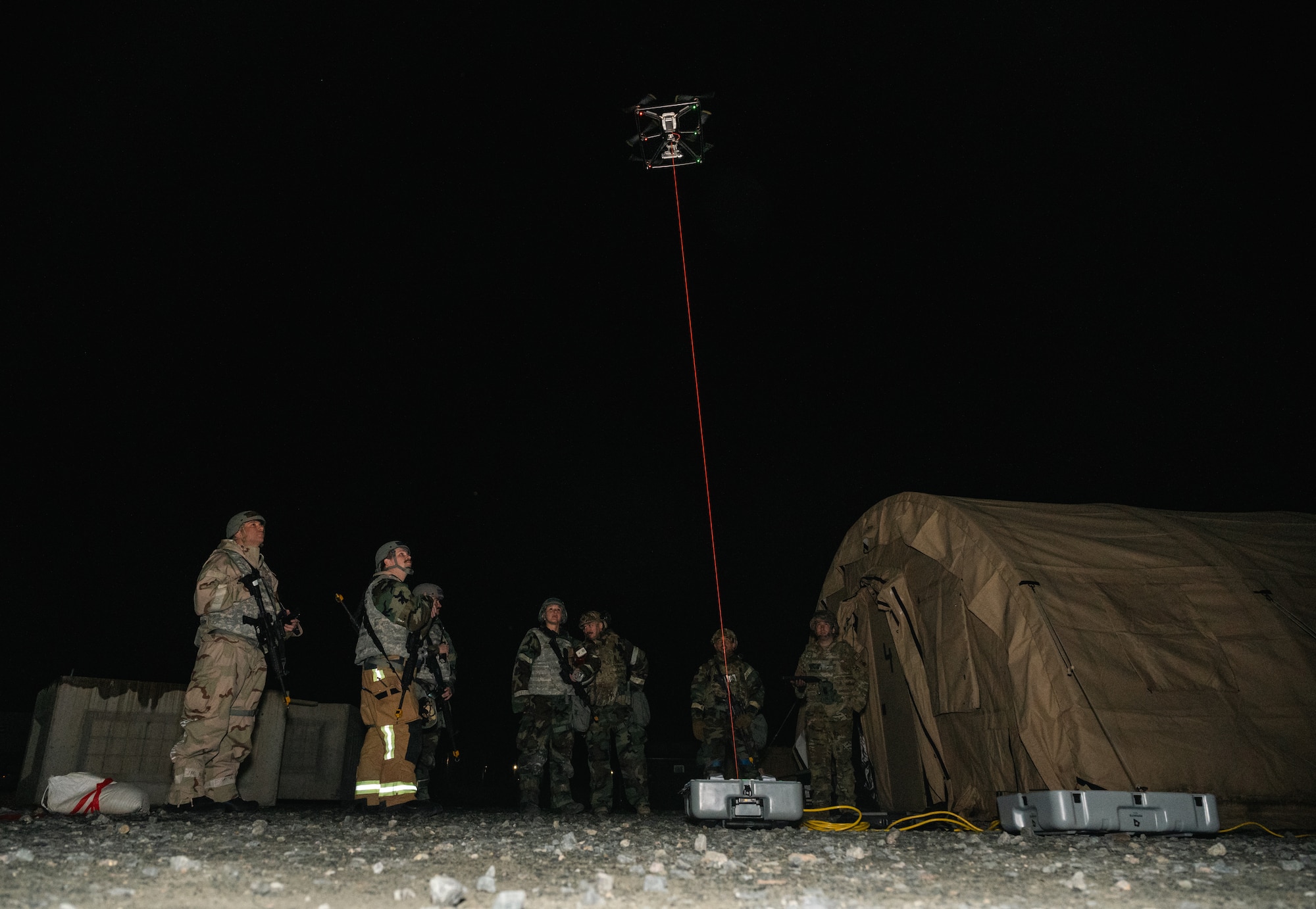 Airmen stare at tethered drone in the night