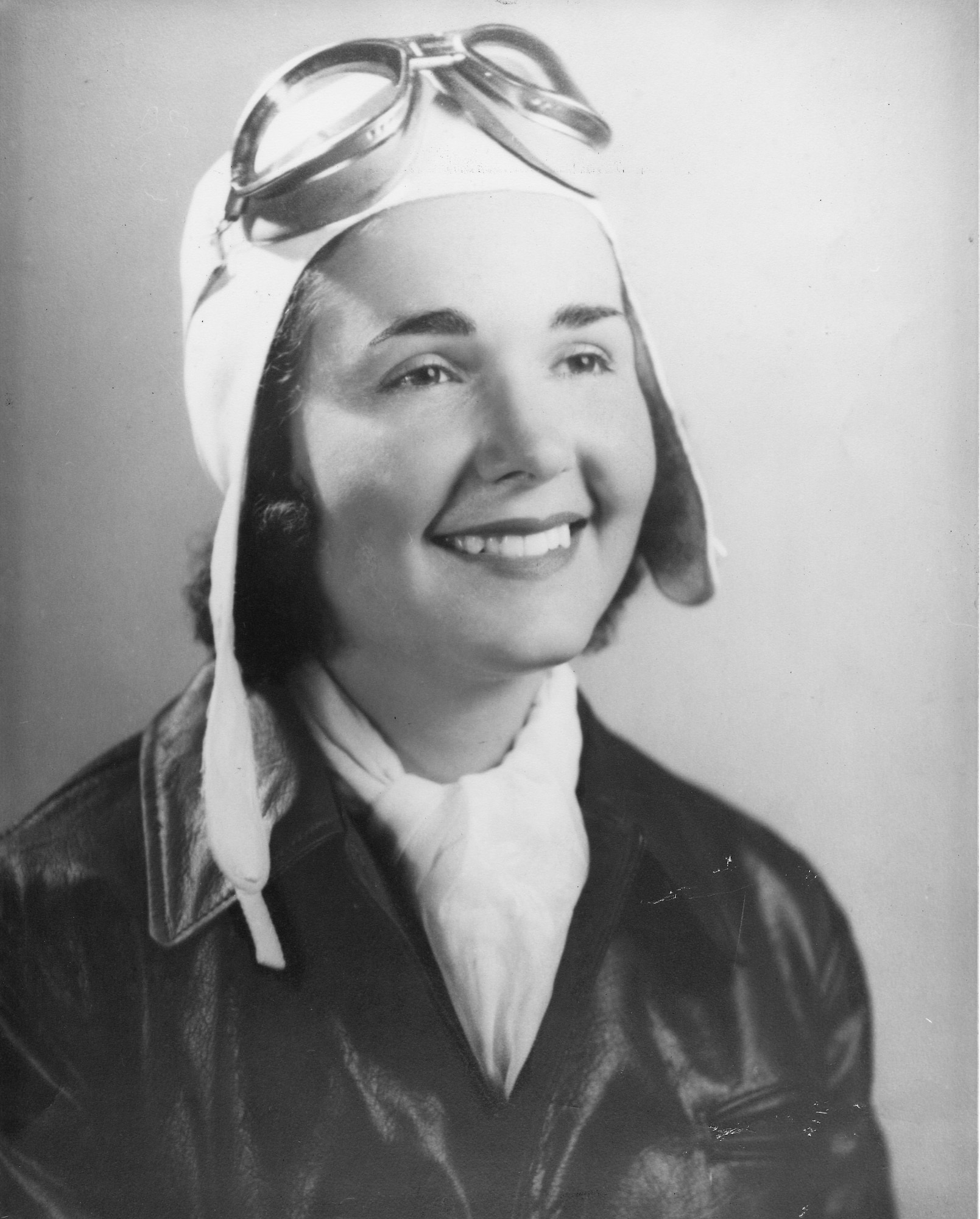 portrait of Marie Barrett wearing her flight cap and goggles, white flight scarf, and leather flying jacket.