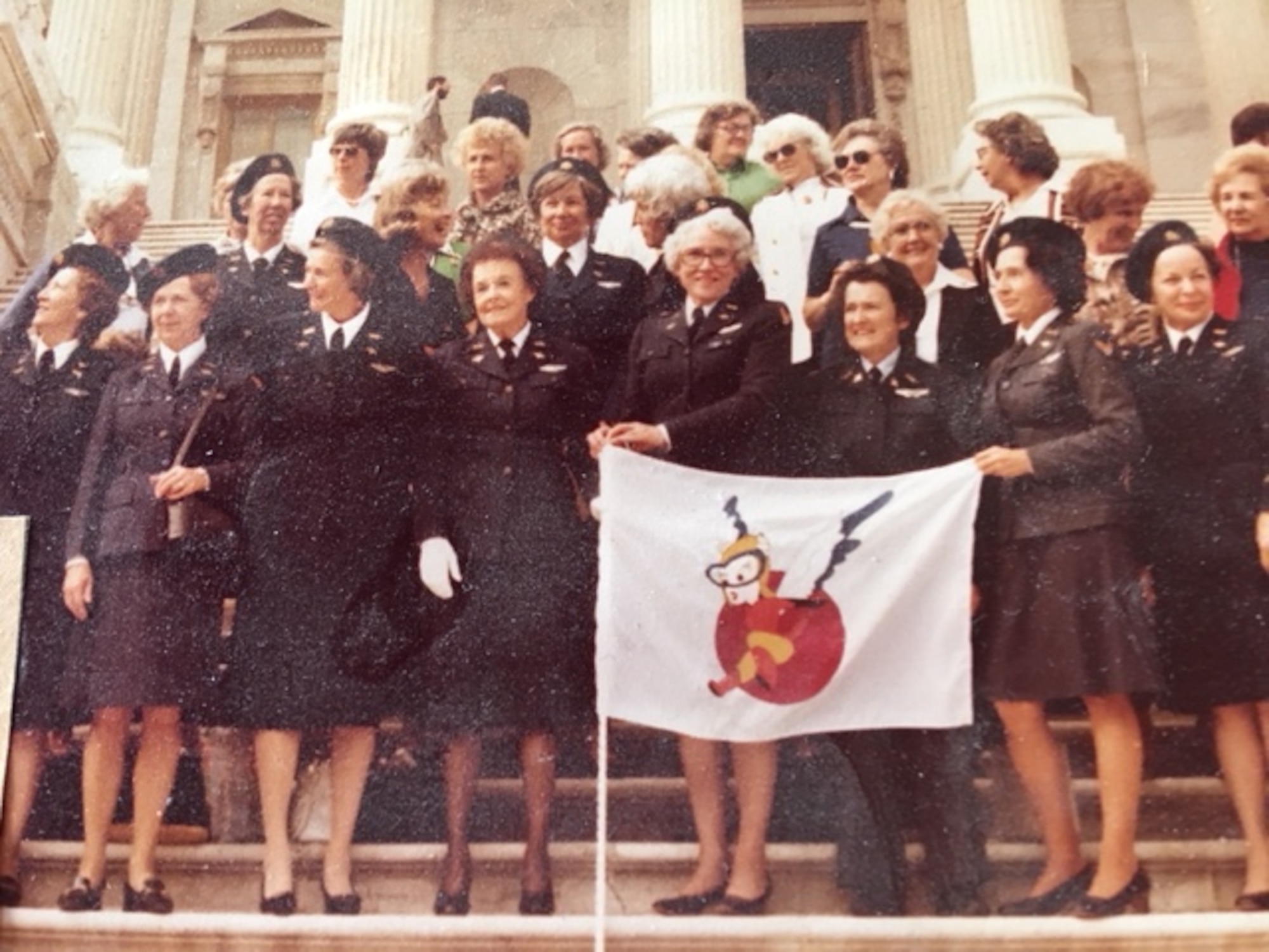 Group of WASPs standing on the steps of the US Capitol holding a banner.