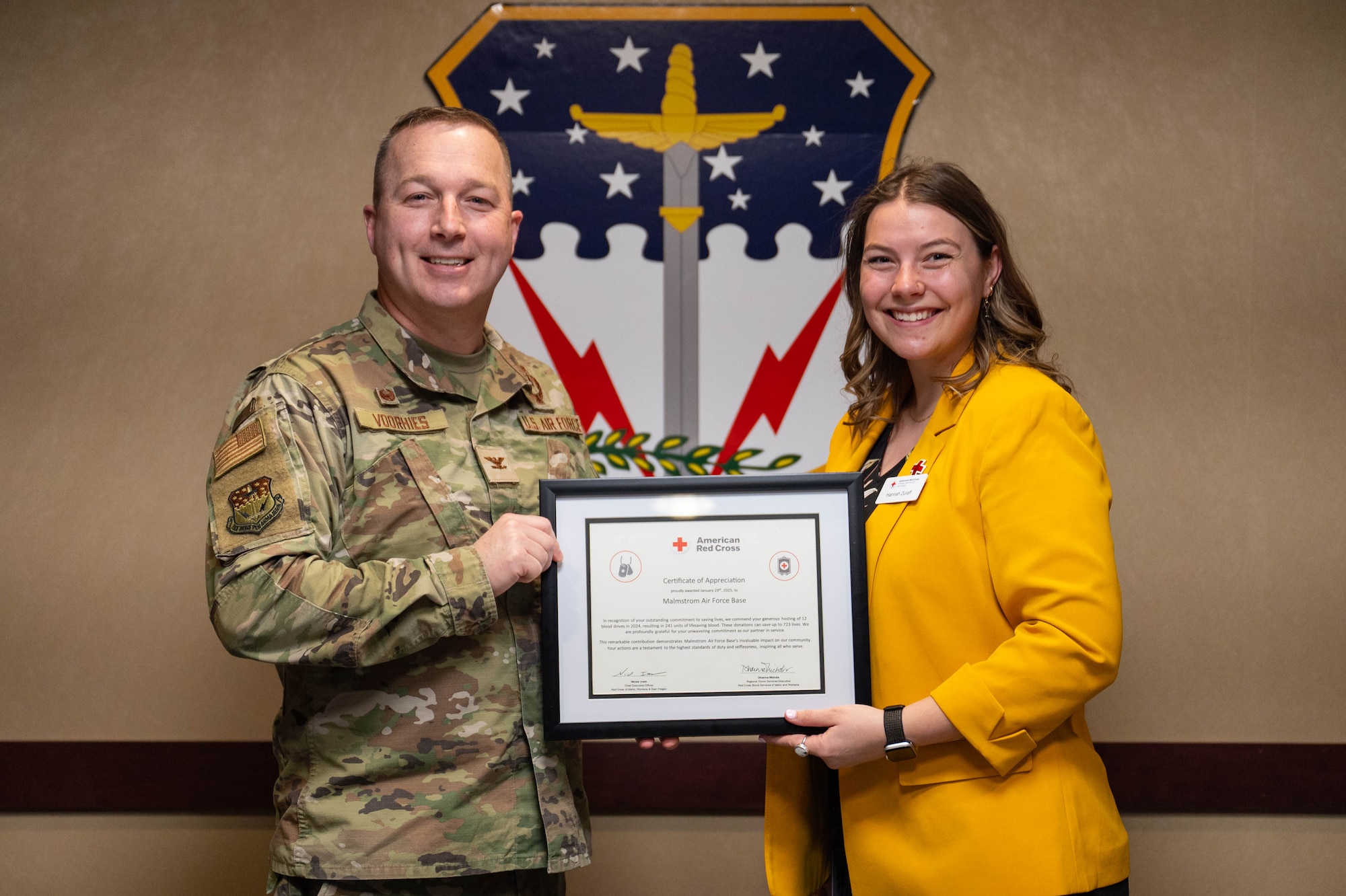 A man and woman stand together holding a certificate of appreciation.