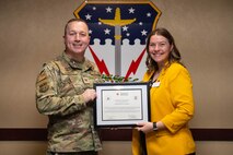 A man and woman stand together holding a certificate of appreciation.