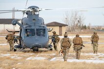 A group of uniformed personnel walk back to a helicopter.