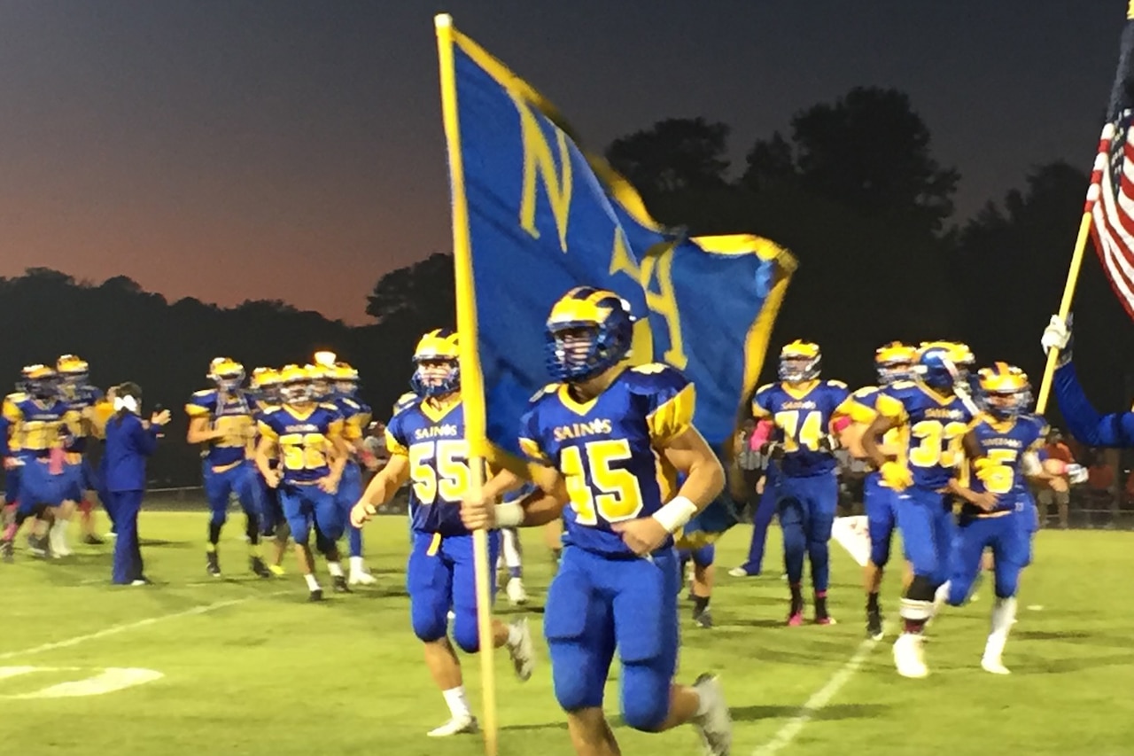 Football players run onto a field.