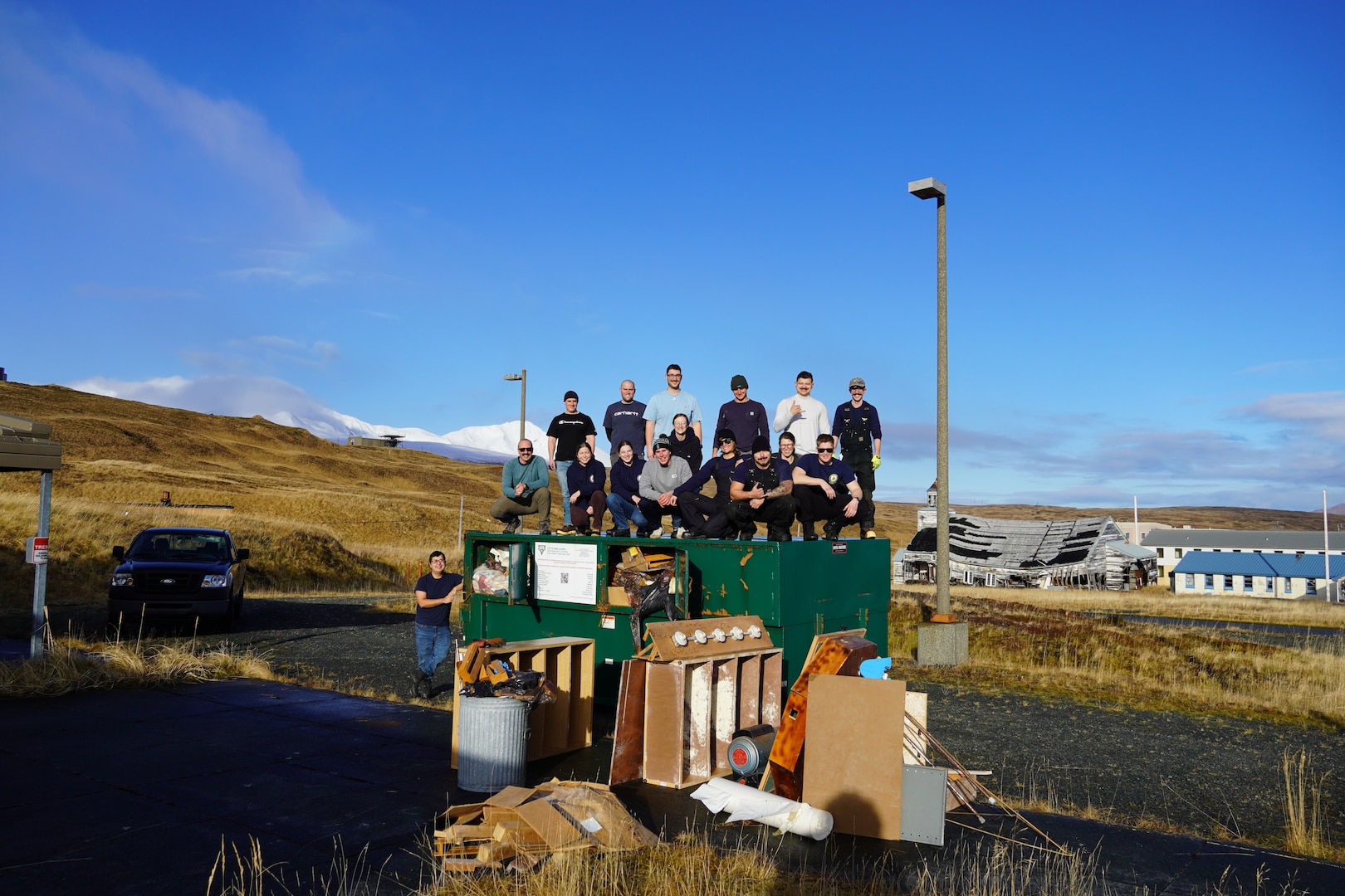 Coast Guard Cutter Bertholf (WMSL 750) crew members pose with debris they removed from a building being refurbished as a community tsunami shelter in Adak, Alaska, Dec. 20, 2024. Bertholf’s crew members fostered relationships while in port through  community engagement activities. (U.S. Coast Guard photo by Petty Officer First Class Courtney Will.)