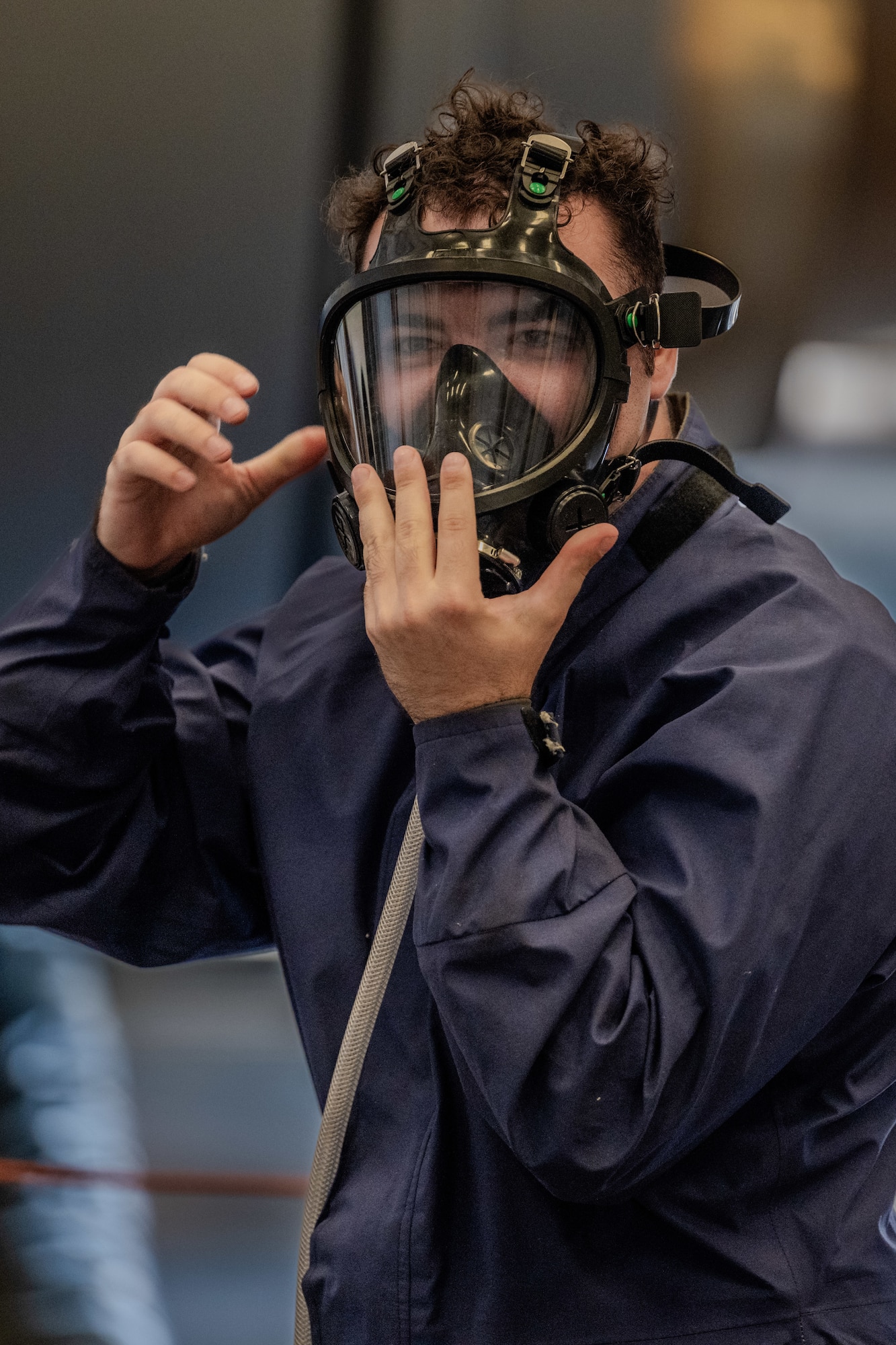 An Airman places his hand on his oxygen mask while wearing it.