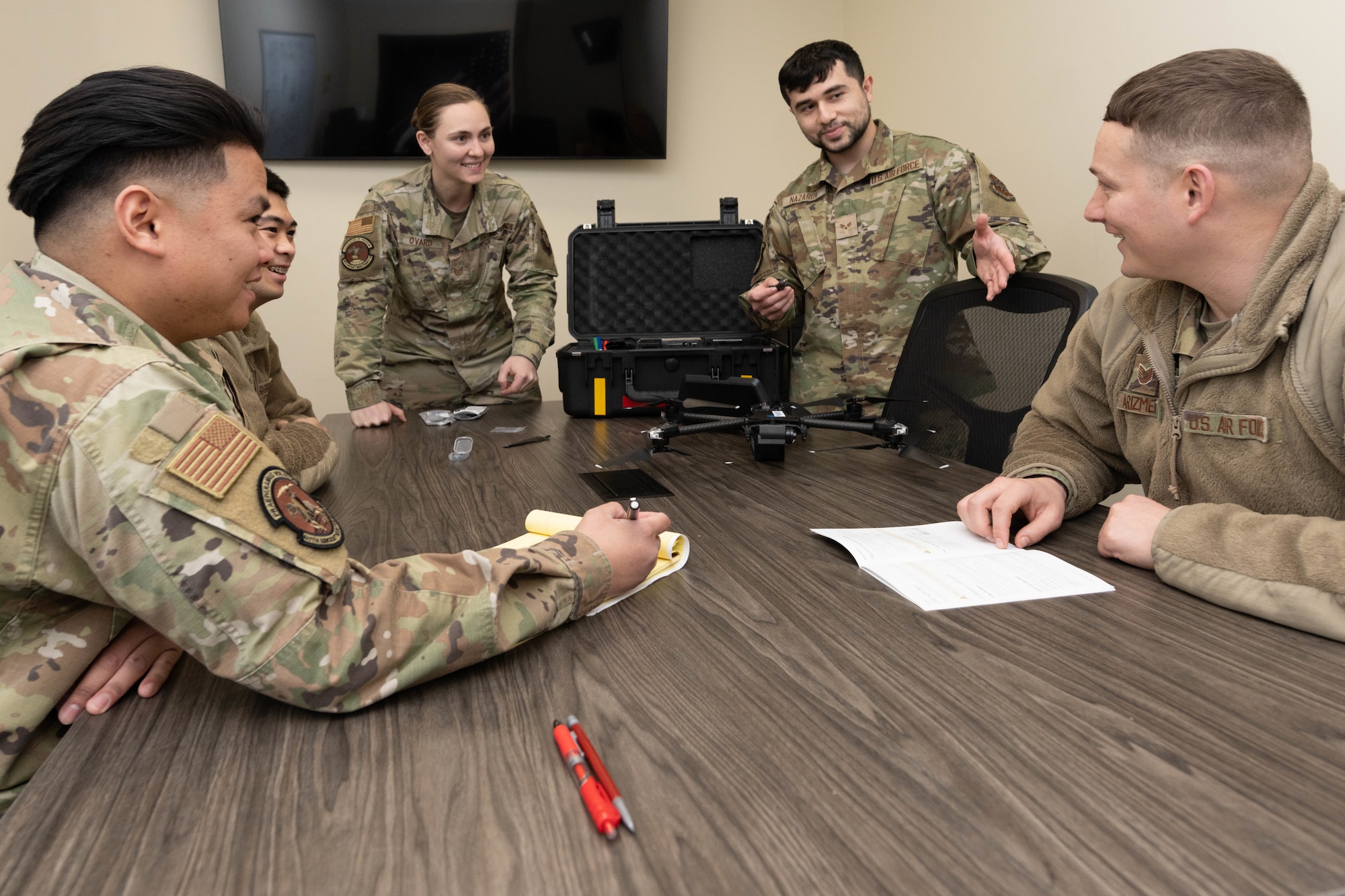 A group of Airmen gather around a table having a discussion