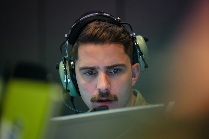 photo of US Airman wearing a headset working on a computer