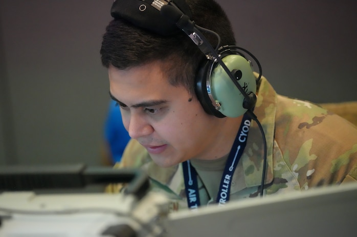 photo of US military member wearing a headset works on a computer