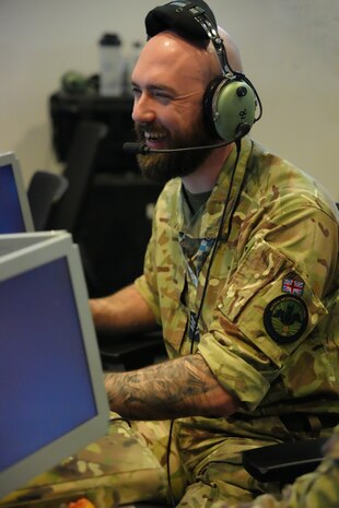 UK military member wearing headset works on a computer