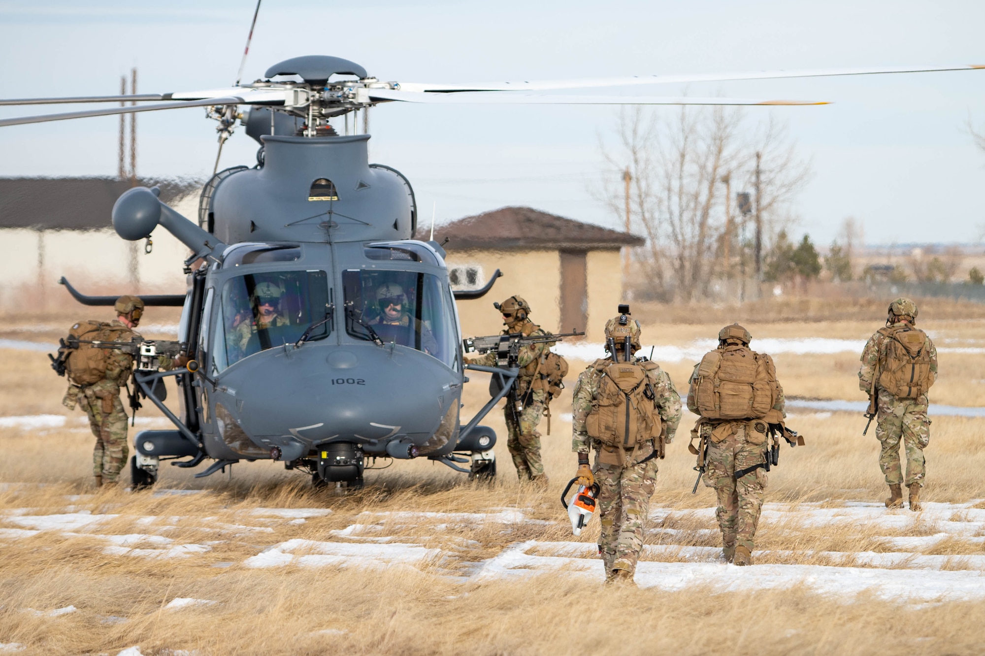 A group of uniformed personnel walk back to a helicopter.