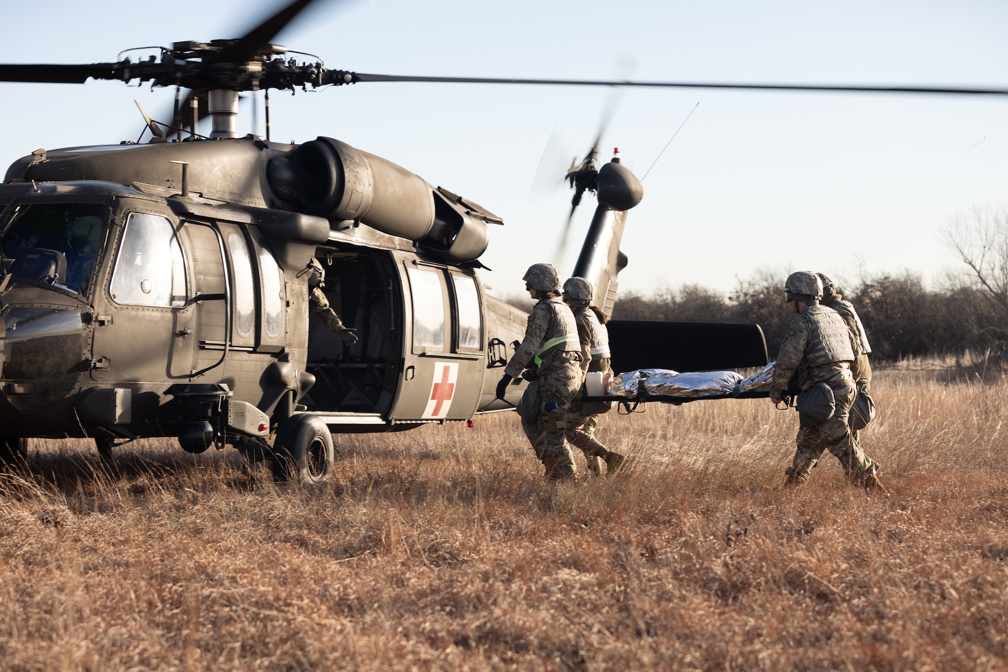 Airmen carrying patient litter toward helicopter