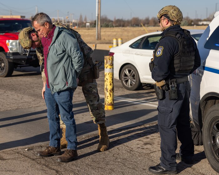 Man in handcuffs being searched by military police