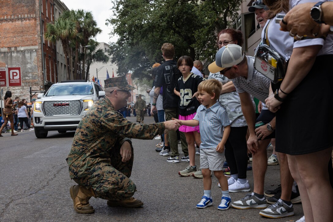 U.S. Marine Corps Gunnery Sgt. Theodore McElwee, production manager for the Marine Forces Reserve Band shakes the hand of a child during the Super Bowl LIX parade, New Orleans, Feb. 8, 2025. The Marine Corps is the lead service for Super Bowl LIX, participating in multiple events throughout the week exhibiting pride leading up to the U.S. Marine Corps’ 250th birthday. (U.S. Marine Corps photo by Sgt. Scott Jenkins)