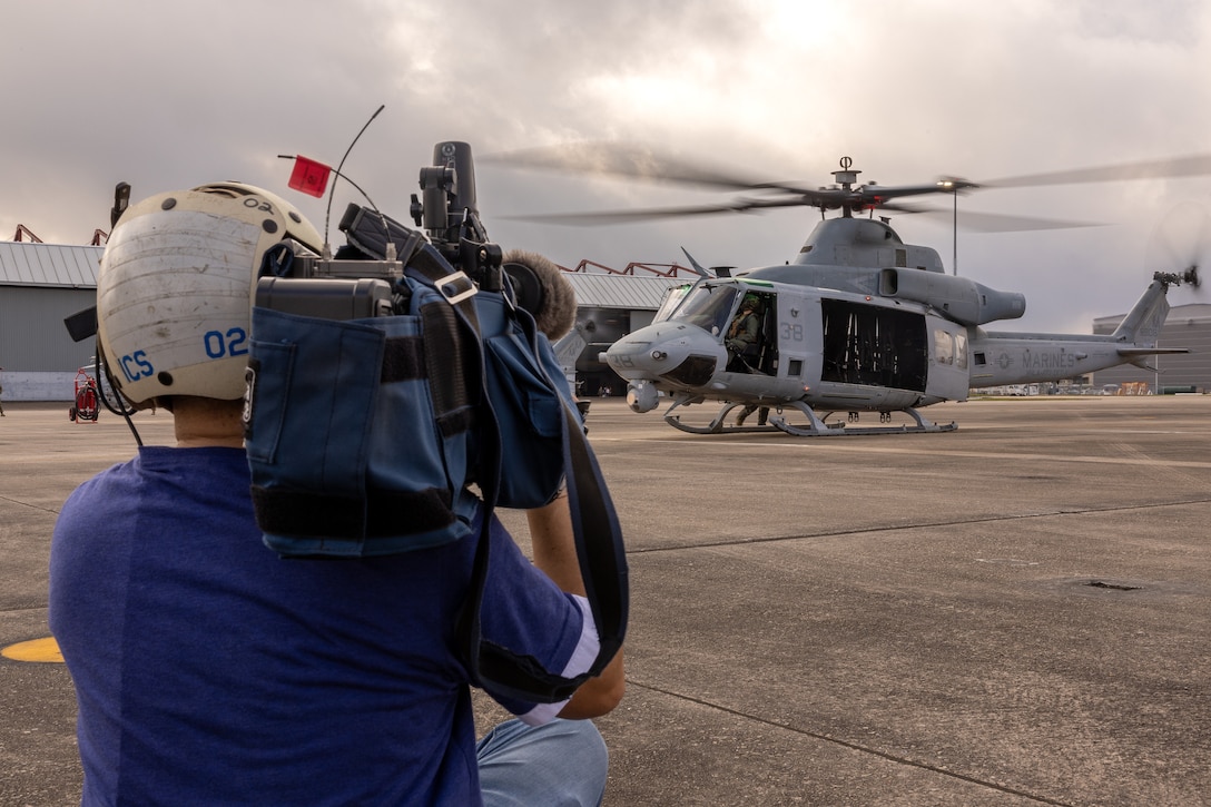 A member of the media documents a UH-Y1 Venom Huey from Light Attack Helicopter Squadron (HMLA) 773, Marine Air Group 49, 4th Marine Aircraft Wing, taking off to perform a formation flight over the Super Bowl LIX parade, New Orleans, Feb. 8, 2025. The Marine Corps is the lead service for Super Bowl LIX, participating in multiple events throughout the week exhibiting pride leading up to the U.S. Marine Corps' 250th birthday. (U.S. Marine Corps photo by Cpl. Aaron TorresLemus)