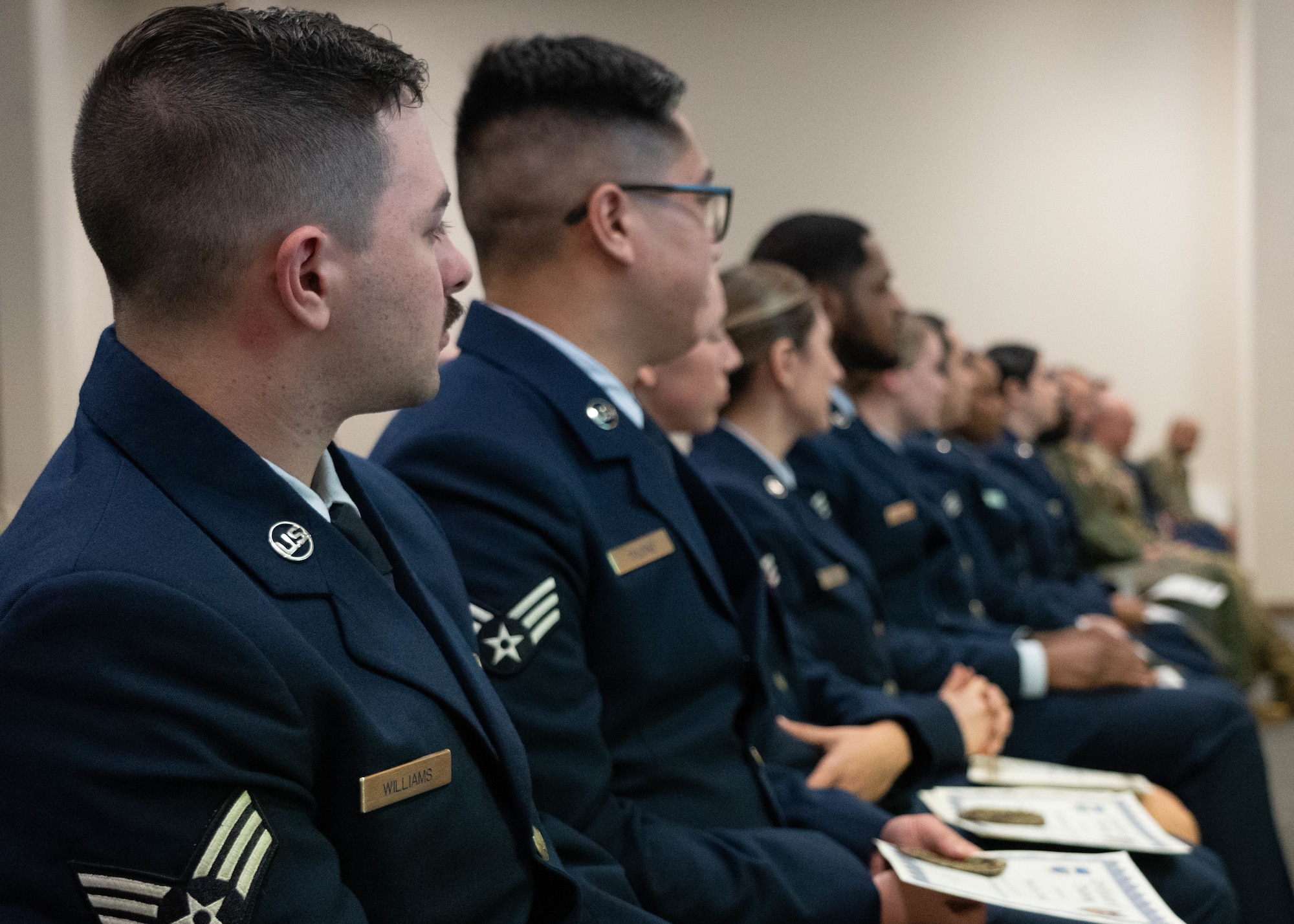Airmen sitting in an auditorium during a graduation ceremony.