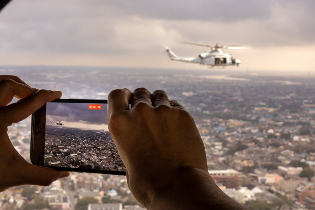A member of the media documents a UH-Y1 Venom Huey from Light Attack Helicopter Squadron (HMLA) 773, Marine Air Group 49, 4th Marine Aircraft Wing, performing a formation flight over the Super Bowl LIX parade, New Orleans, Feb. 8, 2025. The Marine Corps is the lead service for Super Bowl LIX, participating in multiple events throughout the week exhibiting pride leading up the U.S. Marine Corps' 250th birthday. (U.S. Marine Corps photo by Cpl. Aaron TorresLemus)