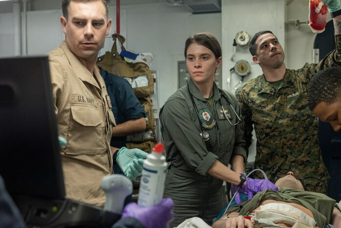U.S. Navy Lt. Cmdr. John Williamson, left, with the amphibious assault ship USS America (LHA 6), Lt. Aviv Freeman, center, a flight surgeon, and Petty Officer Third Class Pedro Rodriguez, a corpsman, both with Marine Medium Tiltrotor Squadron 262 (Rein.), 31st Marine Expeditionary Unit, conduct an ultrasound scan on a simulated casualty during a medical drill aboard the USS America, in the Philippine Sea, Feb. 1, 2025. The drill was conducted to evaluate corpsmen and ship surgeons’ response-and-triage tactics while providing medical care in a variety of simulated scenarios while underway. The America Amphibious Ready Group (ARG), compromising amphibious assault carrier USS America (LHA 6), amphibious transport dock ship USS San Diego (LPD 22), and amphibious dock landing ship USS Rushmore (LSD 47) along with the 31st Marine Expeditionary Unit (MEU), are underway conducting routine integrated operations in U.S. 7th Fleet area of operations. U.S. 7th Fleet is the U.S. Navy’s largest forward-deployed numbered fleet, and routinely interacts and operators with allies and partners to preserve a free and open Indo-Pacific region. (U.S. Marine Corps photo by Pfc. Skilah Sanchez)