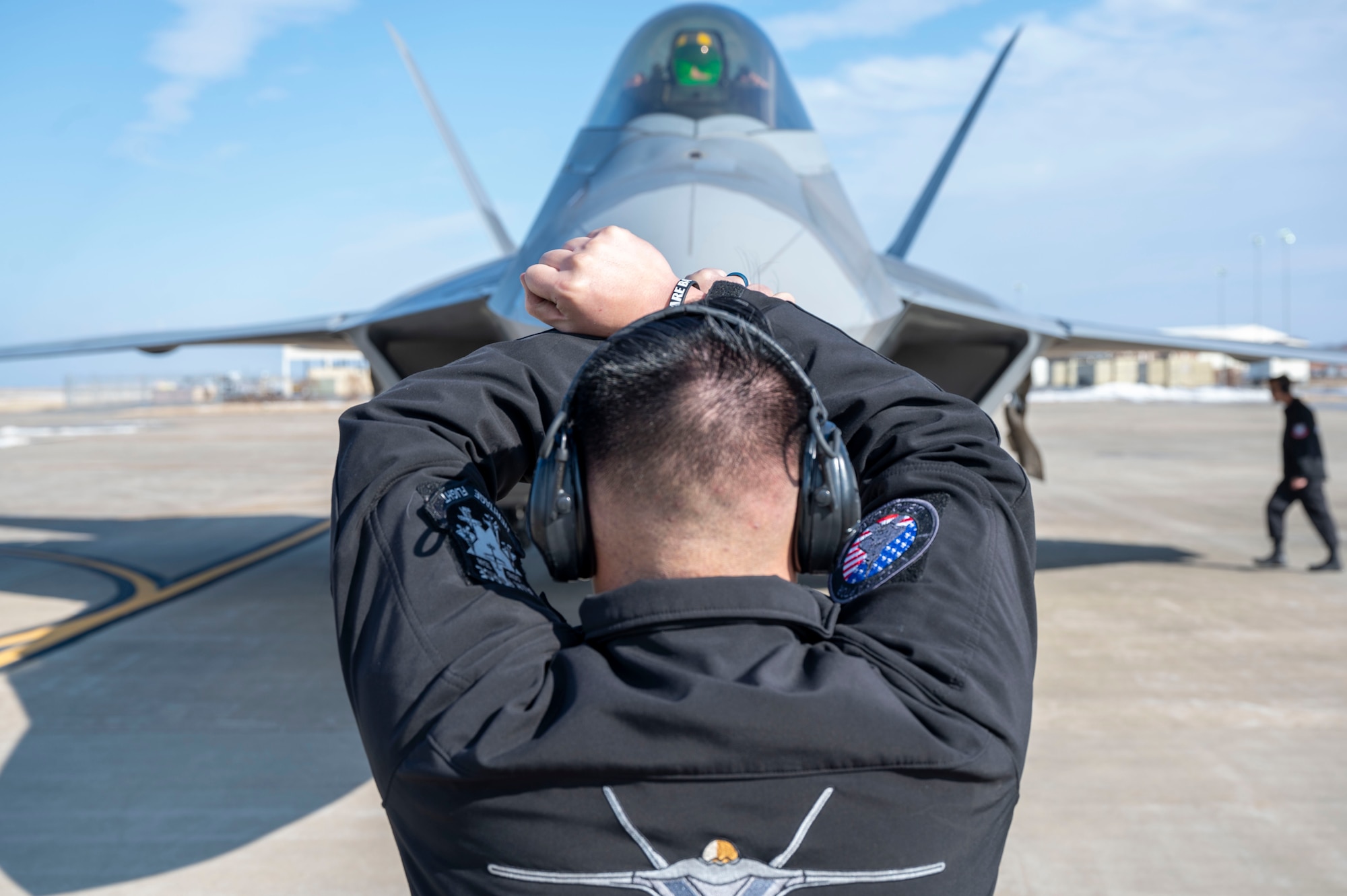 LANGLEY AIR FORCE BASE, Va-- U.S. Air Force Senior Airman Logan Phouangaphayvong, F-22 Raptor Demo Team avionics specialist, marshals Capt. Nick “Laz” Le Tourneau, F-22 Raptor Demo Team commander and pilot, into his parking spot following the team’s certification flight at Langley Air Force Base, Virginia, Jan. 24, 2025. Following the beginning of his Air Force career in 2018, Le Tourneau has over 750 flying hours in various jets such as the T-6 Texan, T-38 Talon and F-22 Raptor. (U.S. Air Force photo by Tech Sgt. Matthew Coleman-Foster)