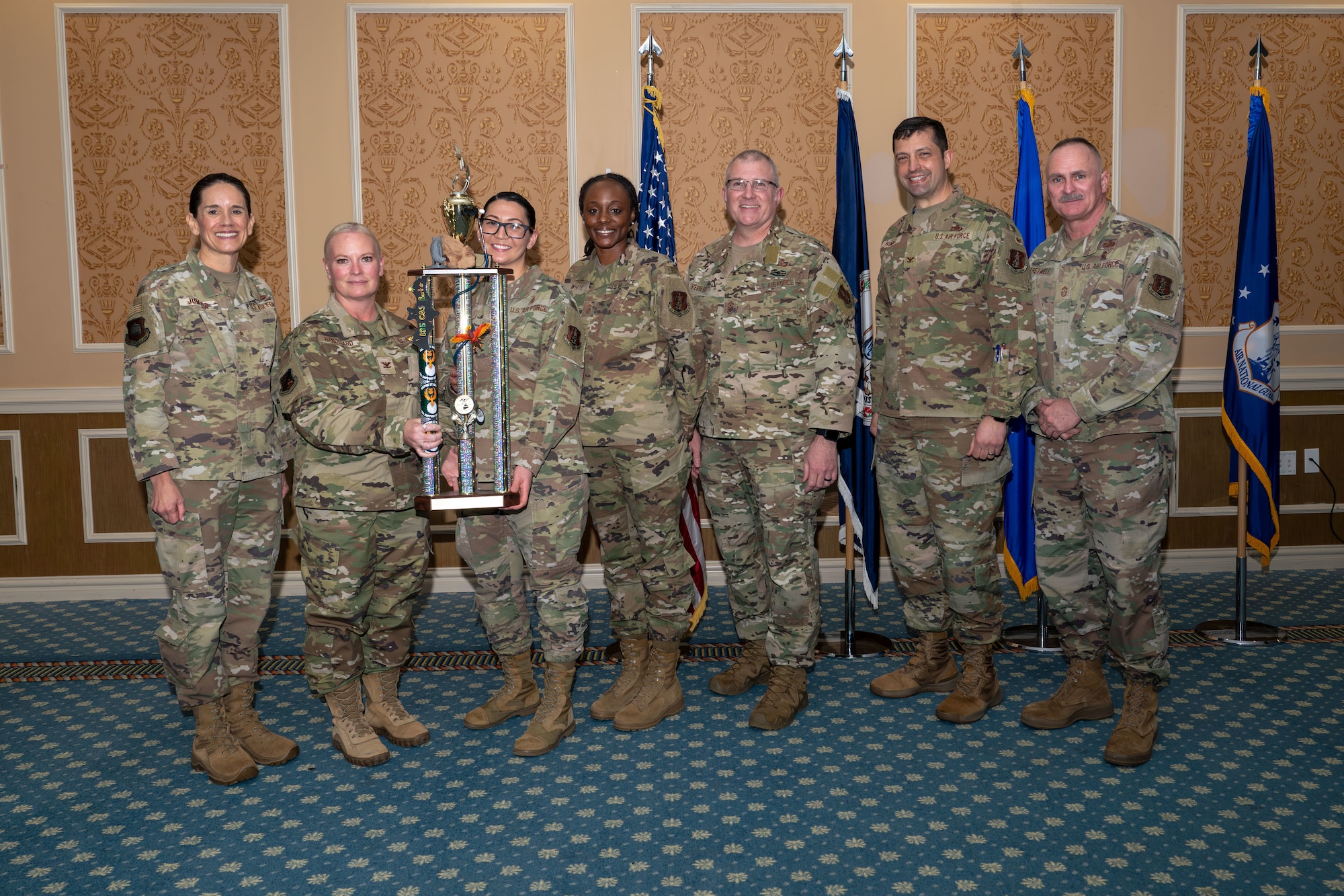 Group of seven Airmen with two holding Toy Drive Trophy.