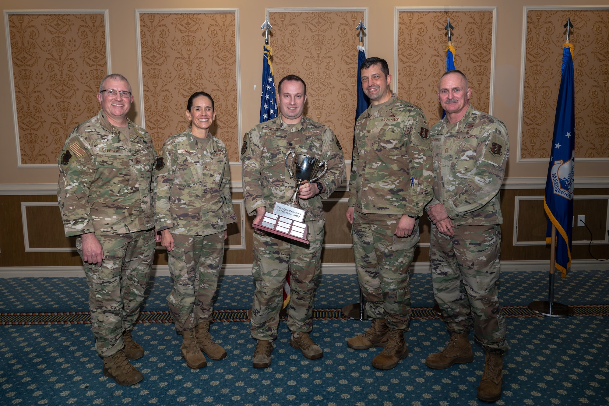 Group of five Airmen with middle holding Adjutant General's Air Readiness Trophy.