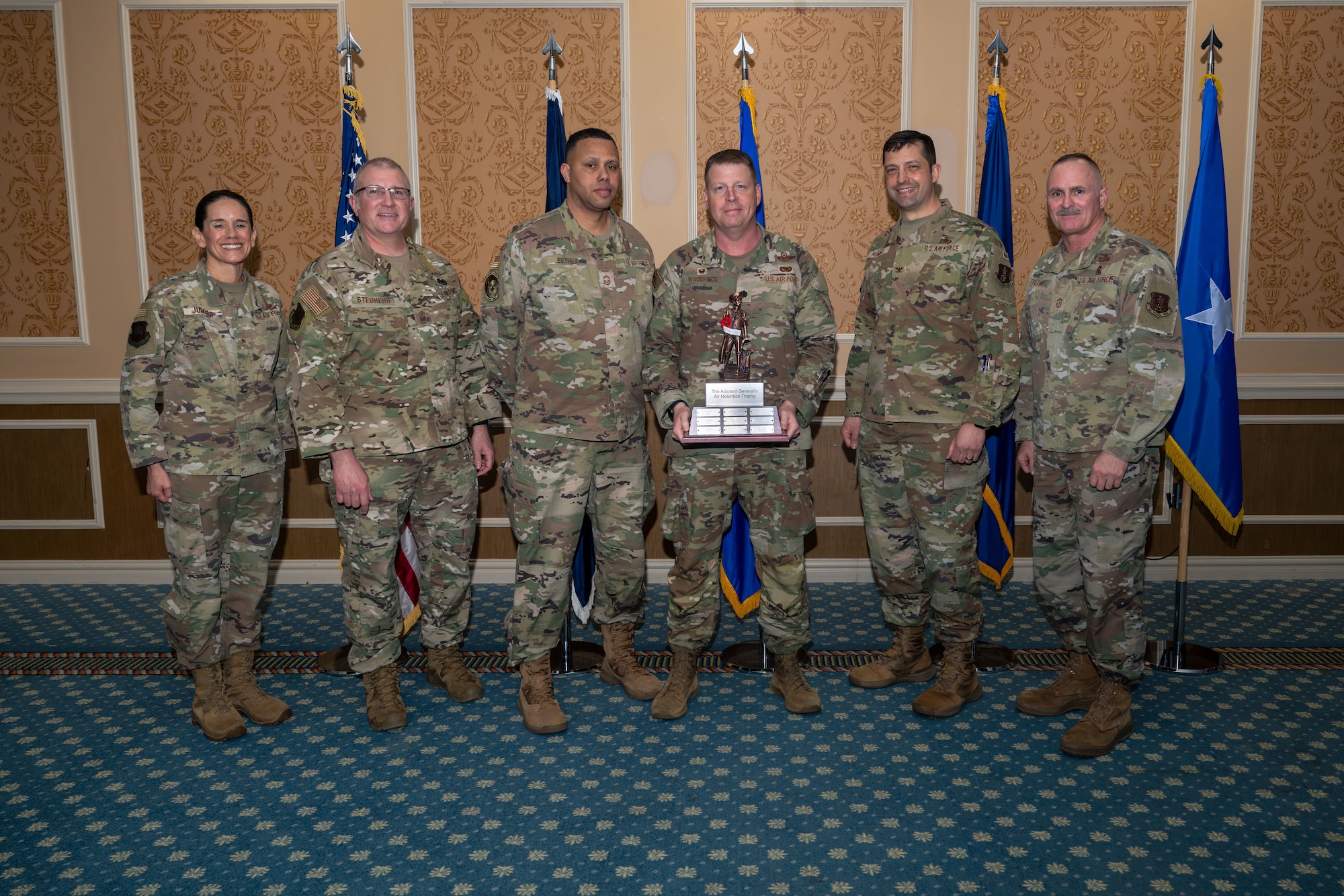Group of six Airmen with one holding Adjutant General's Air Retention Trophy.