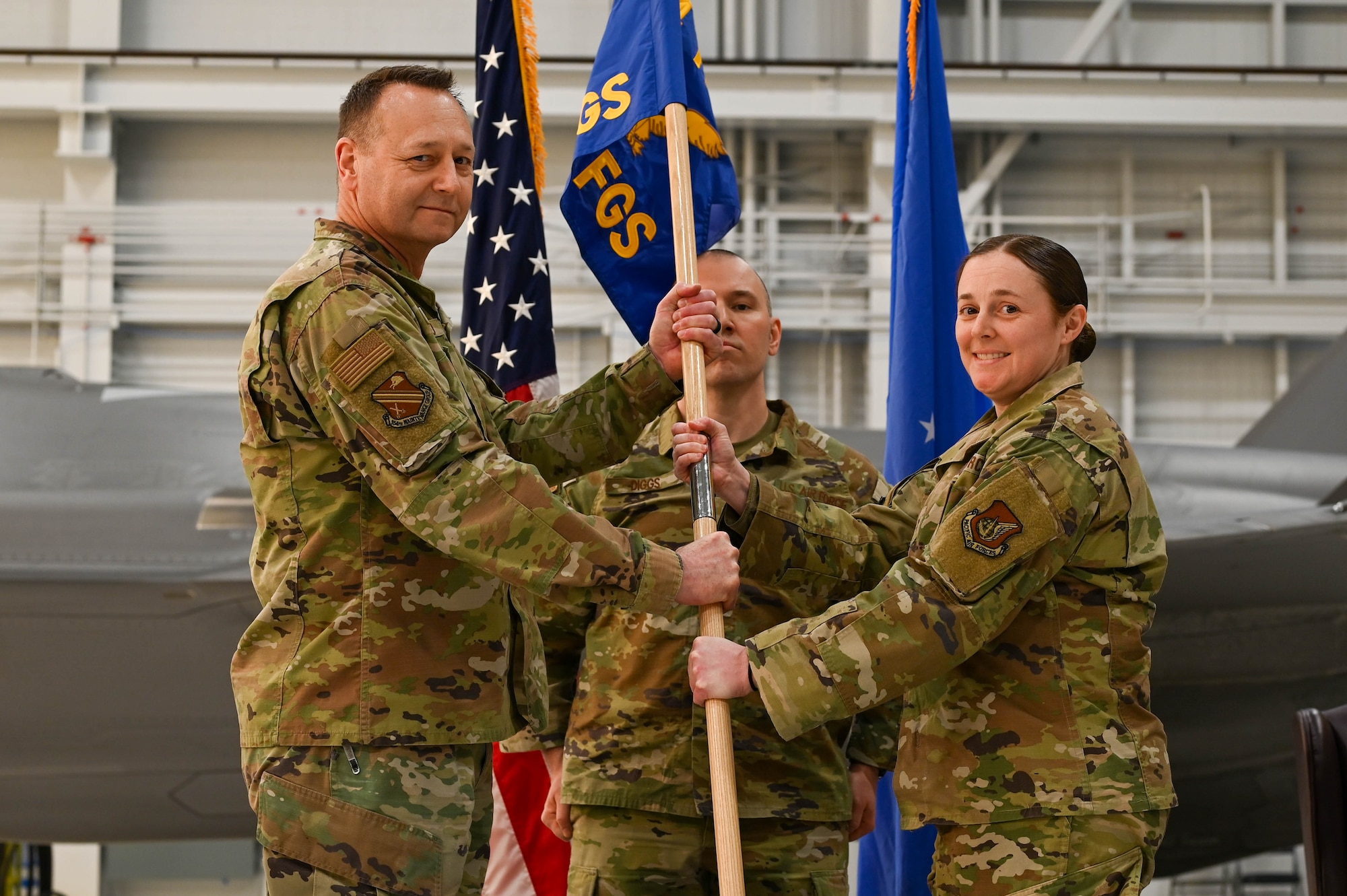 U.S. Air Force Col. Jerrymar Copeland, left, hands the guidon to Maj. Allana Gallant, 355th Fighter Generation Squadron incoming commander, during a change of command ceremony at Eielson Air Force Base, Alaska, Feb. 7, 2025.