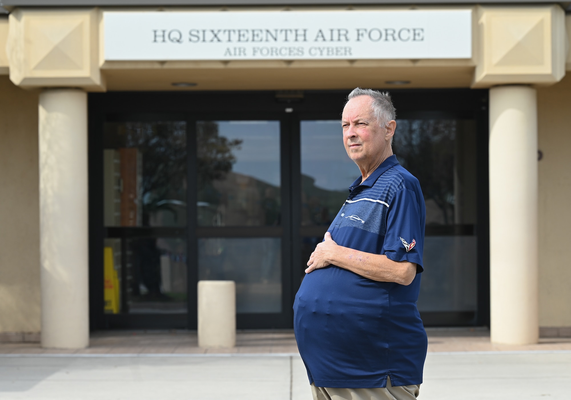 A gentleman with an over-sized mid section due to polycystic disease, sits in an outside break area.