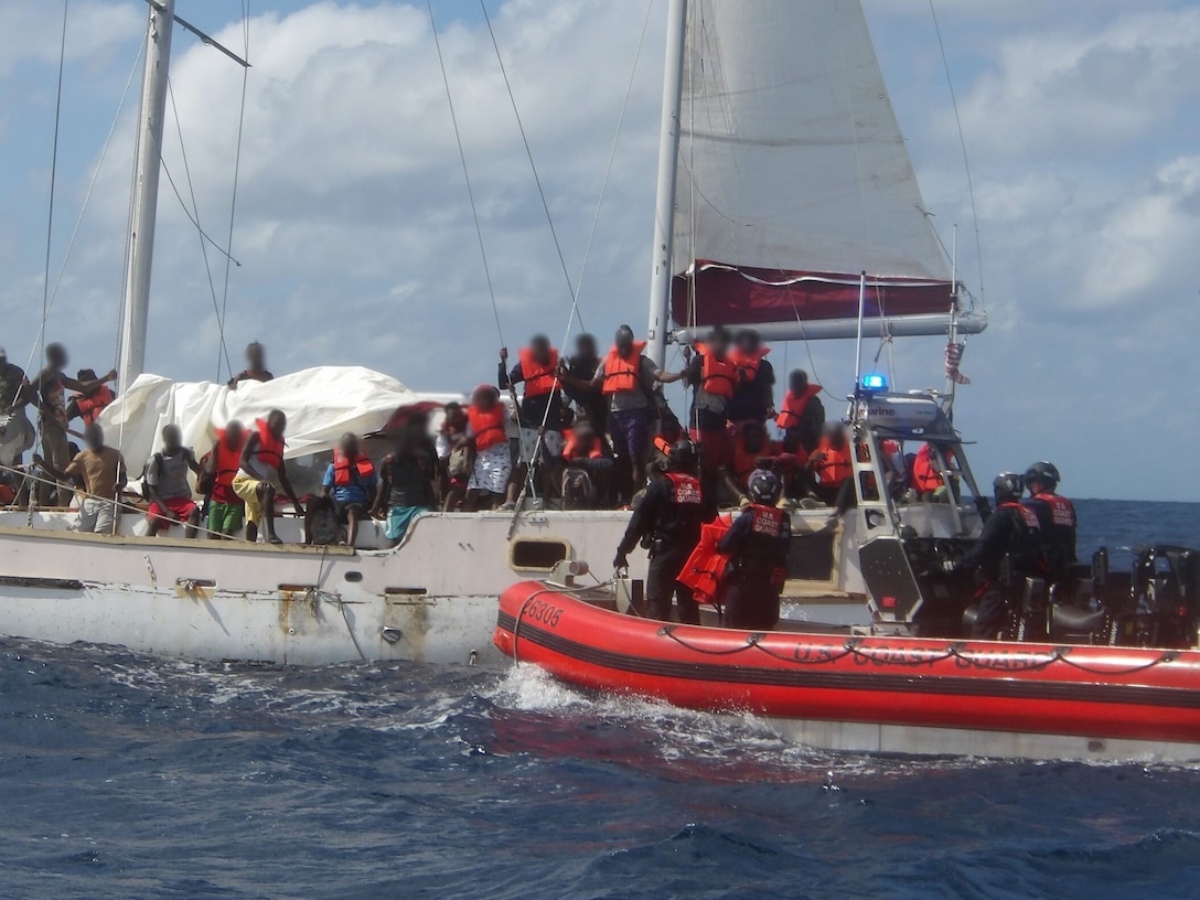 Crewmembers from U.S. Coast Guard Cutter Escanaba distributing personal flotation devices to Haitian aliens on board a 30-foot sailing vessel, in the Caribbean Sea, Feb. 5, 2025. 132 Haitian aliens were repatriated at Cap-Haitien. (U.S. Coast Guard photo)