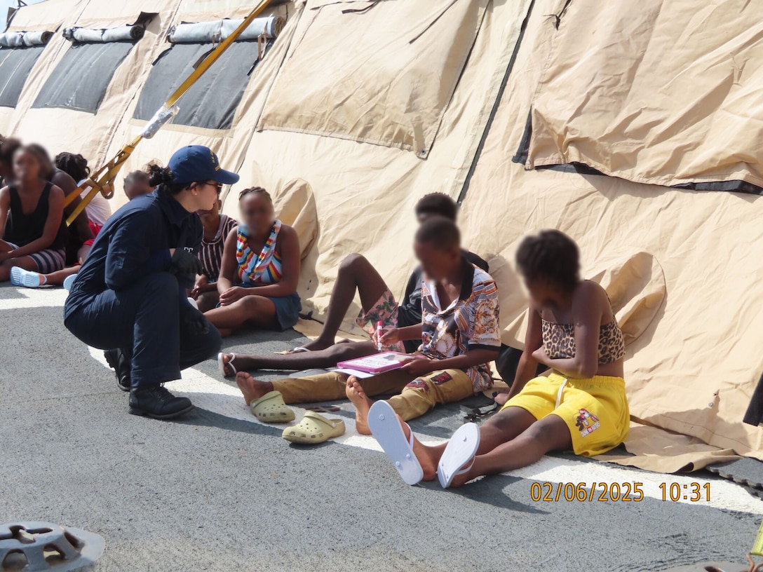 A crewmember from the U.S. Coast Guard Cutter Escanaba checking on multiple Haitian aliens after an interdiction in the Caribbean Sea, Feb. 6, 2025. 132 Haitian aliens were repatriated in Cap-Haitien. (U.S. Coast Guard photo)