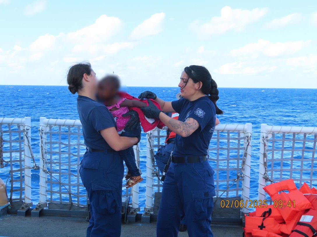 Crewmembers from the U.S. Coast Guard Cutter Escanaba aiding a Haitian child during an interdiction in the Caribbean Sea, Feb. 5, 2025. 132 Haitian aliens were repatriated. (U.S. Coast Guard photo)