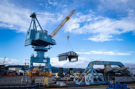A crane lifts the new Trident Refit Facility, Bangor, paint enclosure onto a submarine at Delta Pier, Naval Base Kitsap, Bangor. (U.S. Navy photo by Lonnie Collier, TRFB Public Affairs)