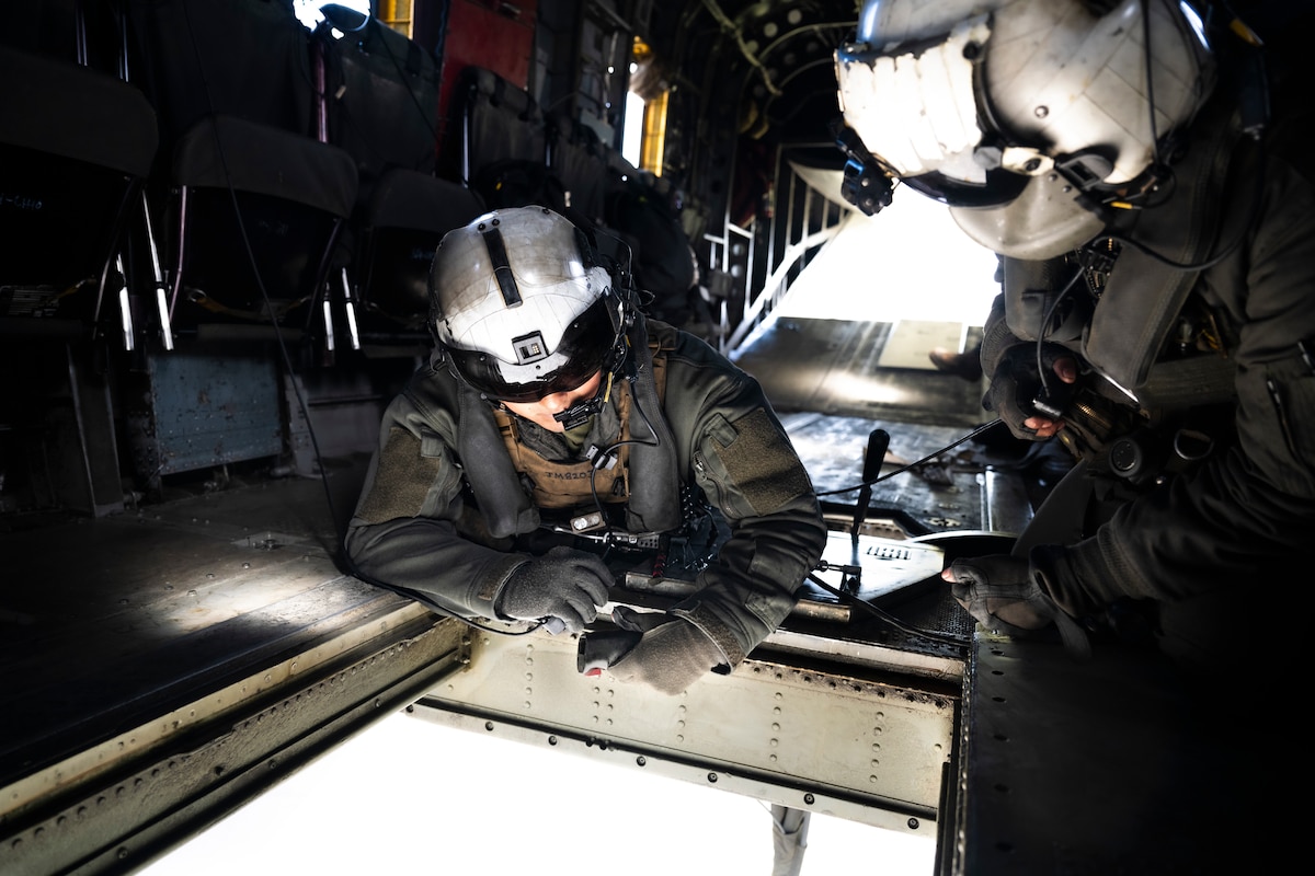 Two crew chiefs look out helicopter window