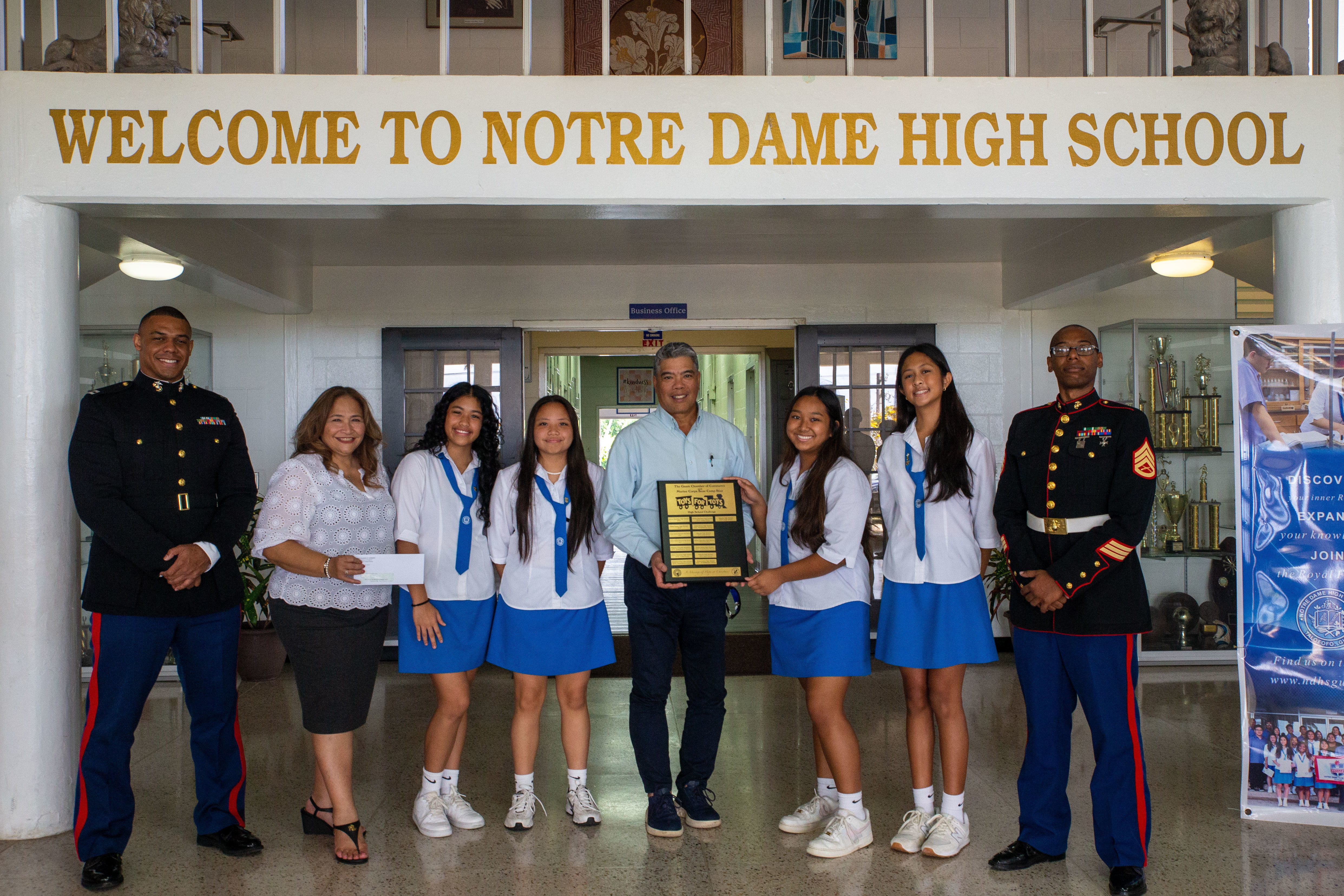 U.S. Marines with Marine Corps Base Camp Blaz, members of Guam Chamber of Commerce, and students with National Honor Society pose for a group photo at Notre Dame High School, Talo’fo’fo, Guam, Jan. 24, 2025.  High schools on Guam participated in a toy collection challenge for Toys for Tots. The high schools that collected the most toys were rewarded with a check from the Guam Chamber of Commerce and the schools name on a Toys for Tots plaque. (U.S. Marine Corps photo by Lance Cpl. Afton Smiley)