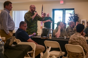 Civilians and military members from the U.S. and foreign countries speaks during a meeting.