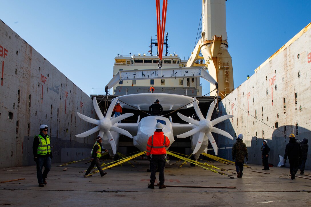 Personnel with Northrop Grumman, US Ocean and Yusen Logistics attach cables to a E-2D Advanced Hawkeye during an aircraft offloading at the Marine Corps Air Station Iwakuni harbor, Japan, Jan. 29, 2025. MCAS Iwakuni is the only Marine Corps installation with a deep-water port and an airfield, giving the air station a unique position to support the dynamic transportation of various military assets throughout the Indo-Pacific. (U.S. Marine Corps photo by Lance Cpl. David Getz)
