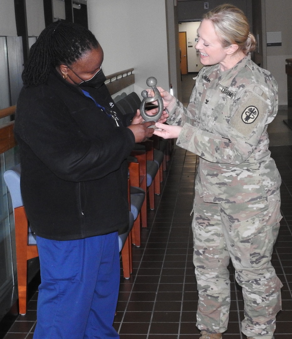 U.S. Army Col. Wendy Woodall (right), director for nursing and chief nursing officer at Walter Reed, presents Caroline Luyimbazi of Cardiology Service with the Healer's Touch Award on February 6 as part of being recognized as a DAISY Award winner after a colleague nominated her for the award.