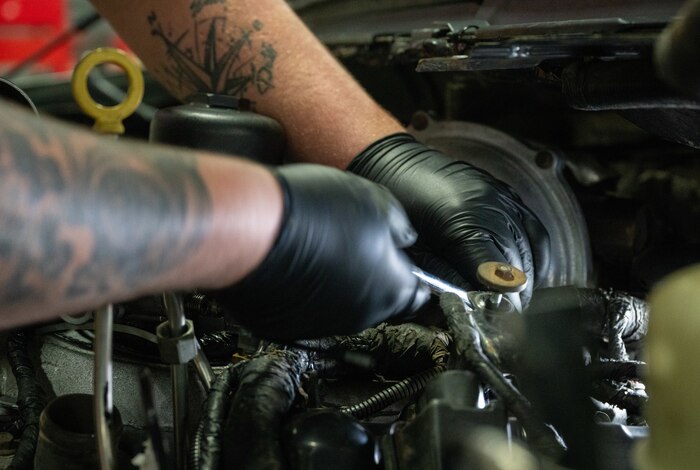 A close up image of a vehicle maintainer working on a truck engine