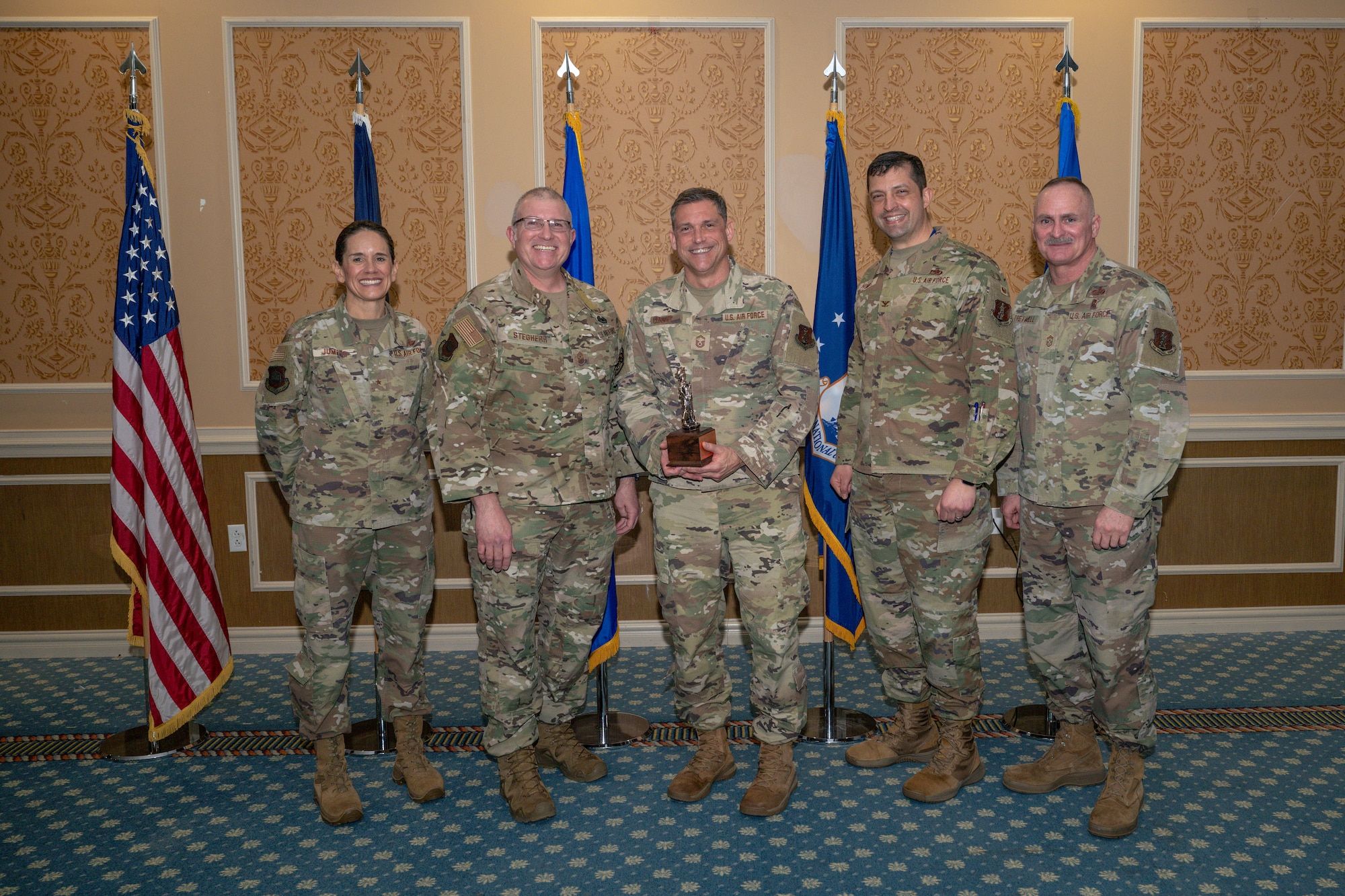 Group of 5 Airmen with center holding Outstanding Senior Noncommissioned Officer of the Year Award