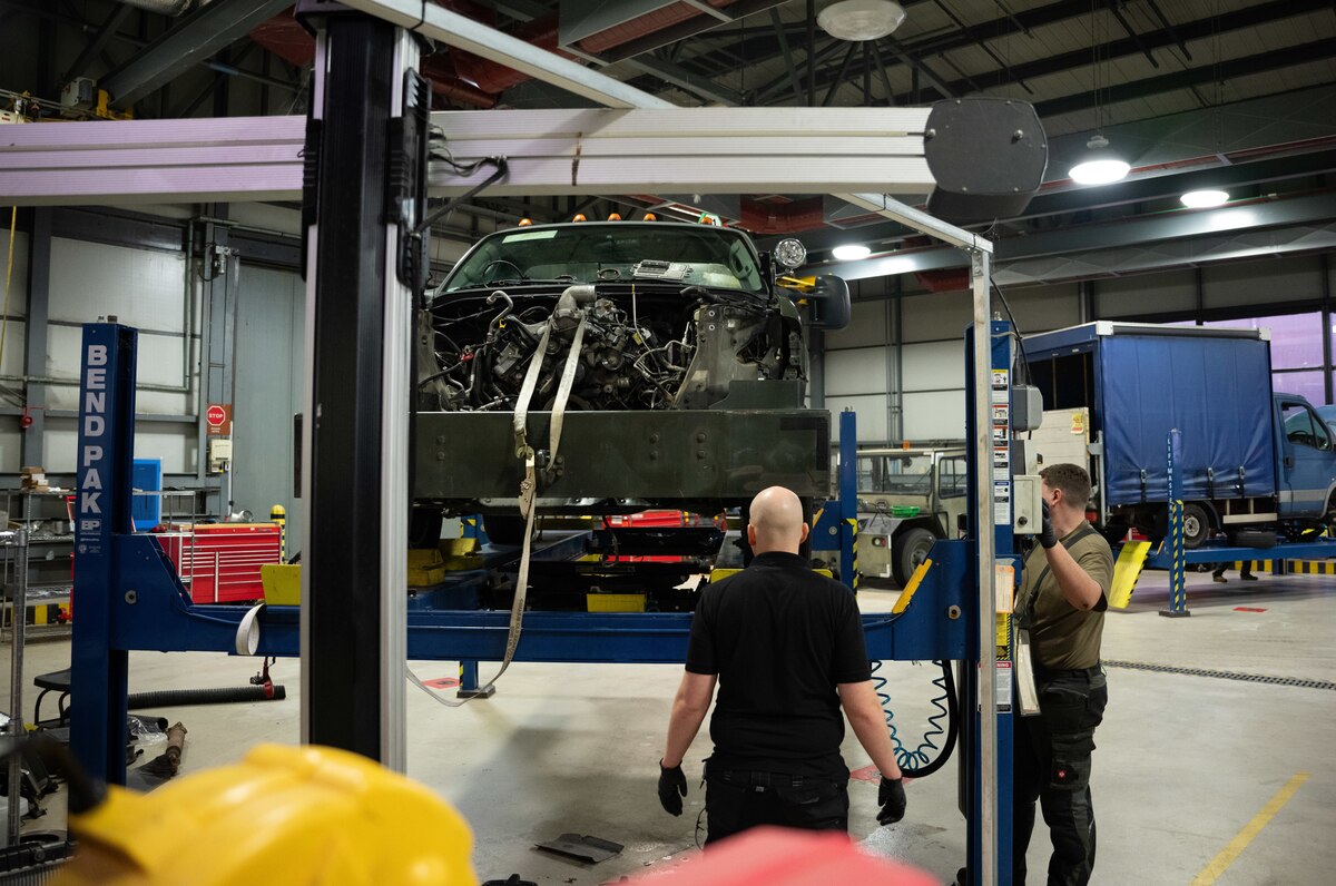 Two vehicle maintairs raise a bobtail truck using a vehicle lift