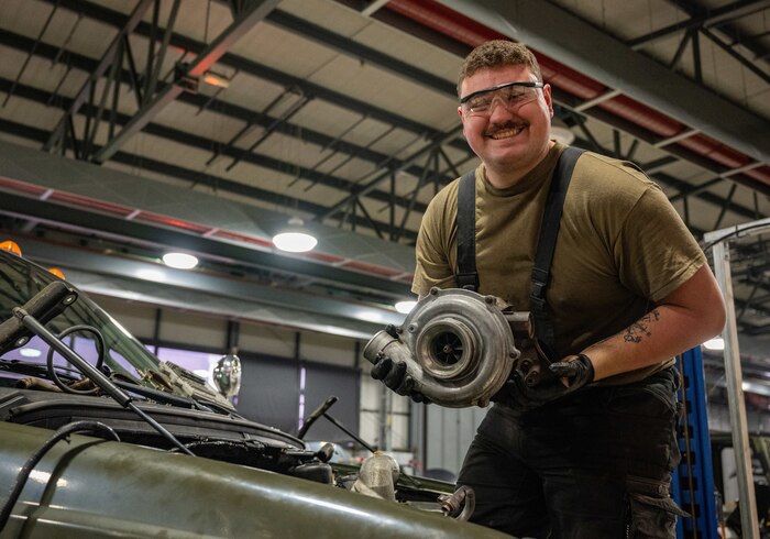 Vehicle maintainers holds a part of a trunck engine