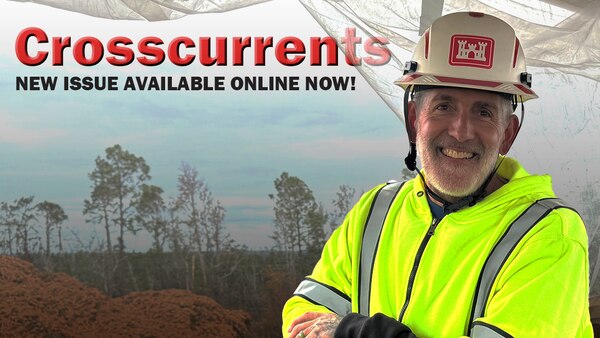 A man in a hard hat and reflective vest stands outside. The text reads "Crossurrents New issue available online now!"