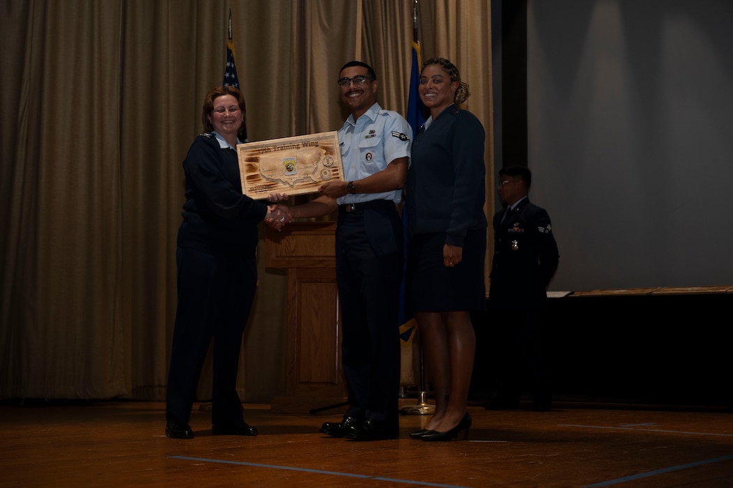 U.S. Air Force Col. Angelina Maguinness, 17th Training Wing commander, and Chief Master Sgt. Khamillia A. Washington, 17th TRW command chief, present Airman 1st Class Knickolas Reider with the Honor Guard Member of the Quarter award at Commander’s All-Call and the 4th Quarterly Awards Ceremony at the base theater, Goodfellow Air Force Base, Texas, Feb. 7, 2025. Before the ceremony, Maguinness, and Washington, took the floor for the Commander’s All-Call. (U.S. Air Force photo by Senior Airman Sarah Williams)