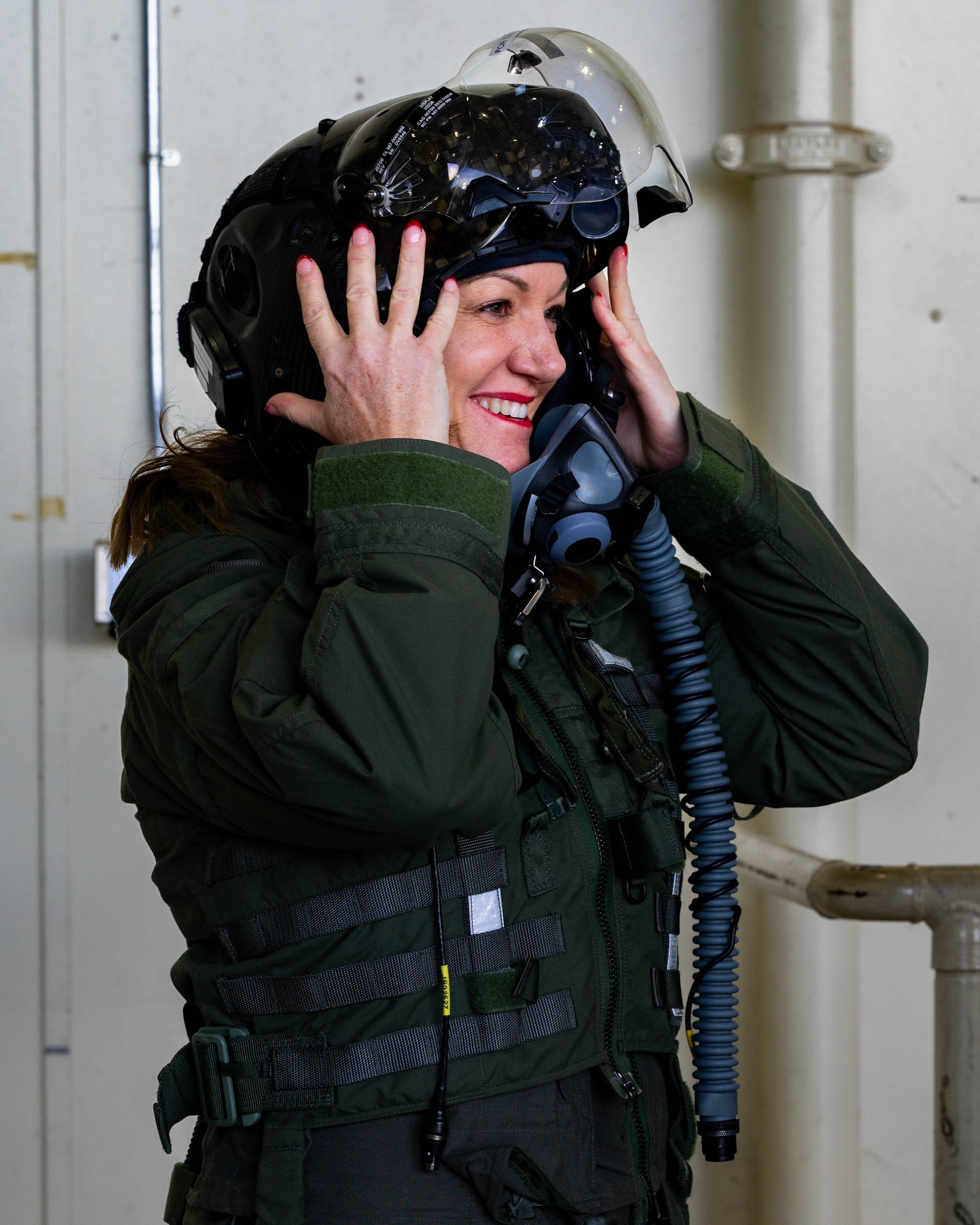 A guest of the 56th Fighter Wing Honorary Commander Immersion, dons a flight suit and high-tech pilot helmet during a briefing on aircrew flight equipment.