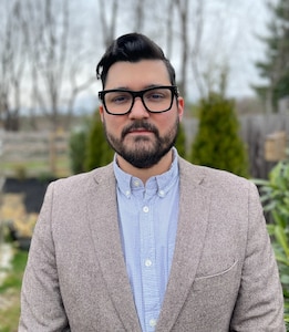 Professional male headshot with a nature background