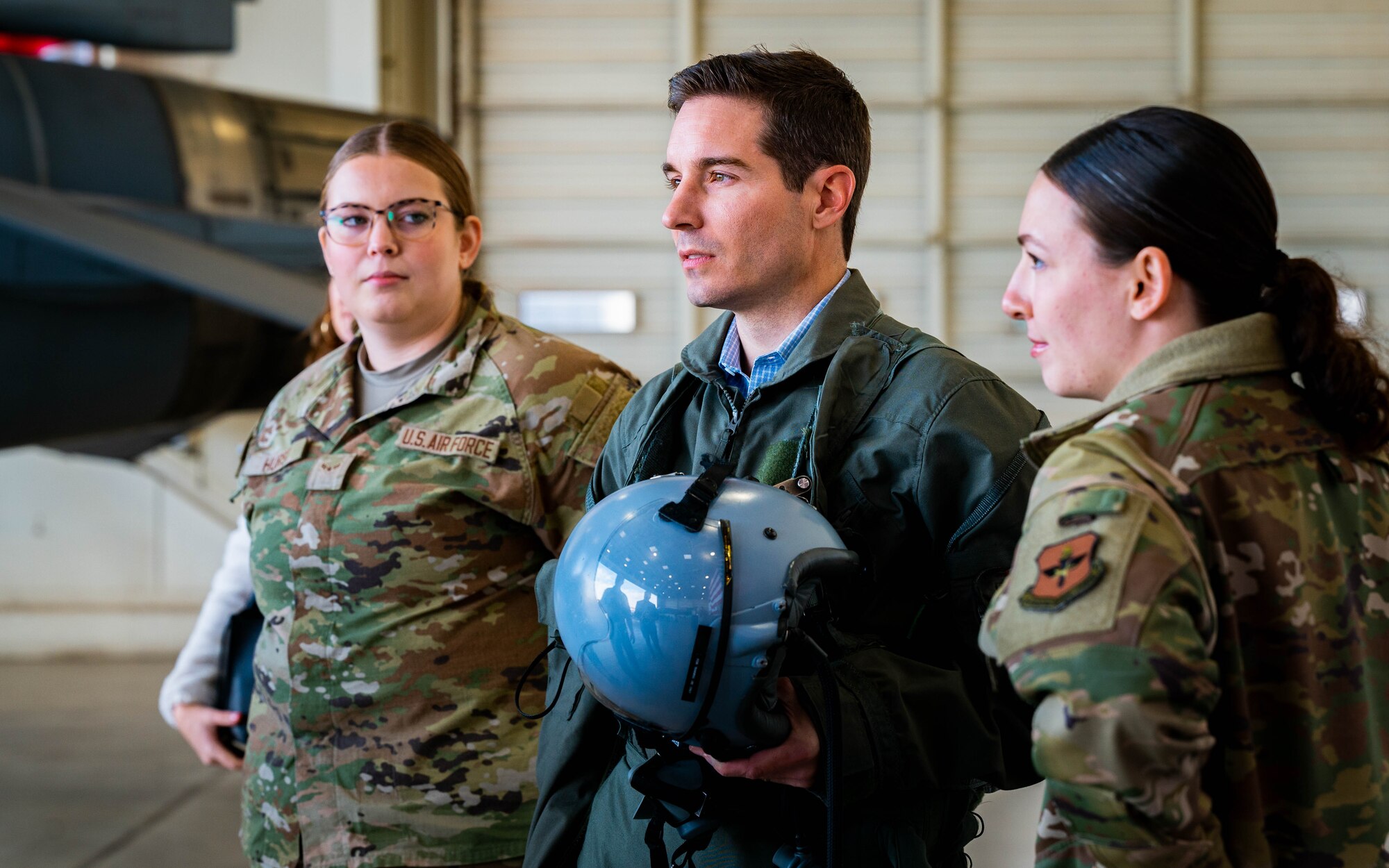 U.S. Air Force Airman 1st Class Lily Hurst (left) and Airman 1st Class Ivy Lawless (right), 56th Operations Support Squadron aircrew flight equipment apprentices, assist Kyle Day, 56th Fighter Wing honorary commander (middle), during an immersion tour.