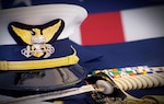 A Coast Guard Officer's hat, sword, gloves and ribbons are displayed together with the American Flag. (U.S. Coast Guard photo)