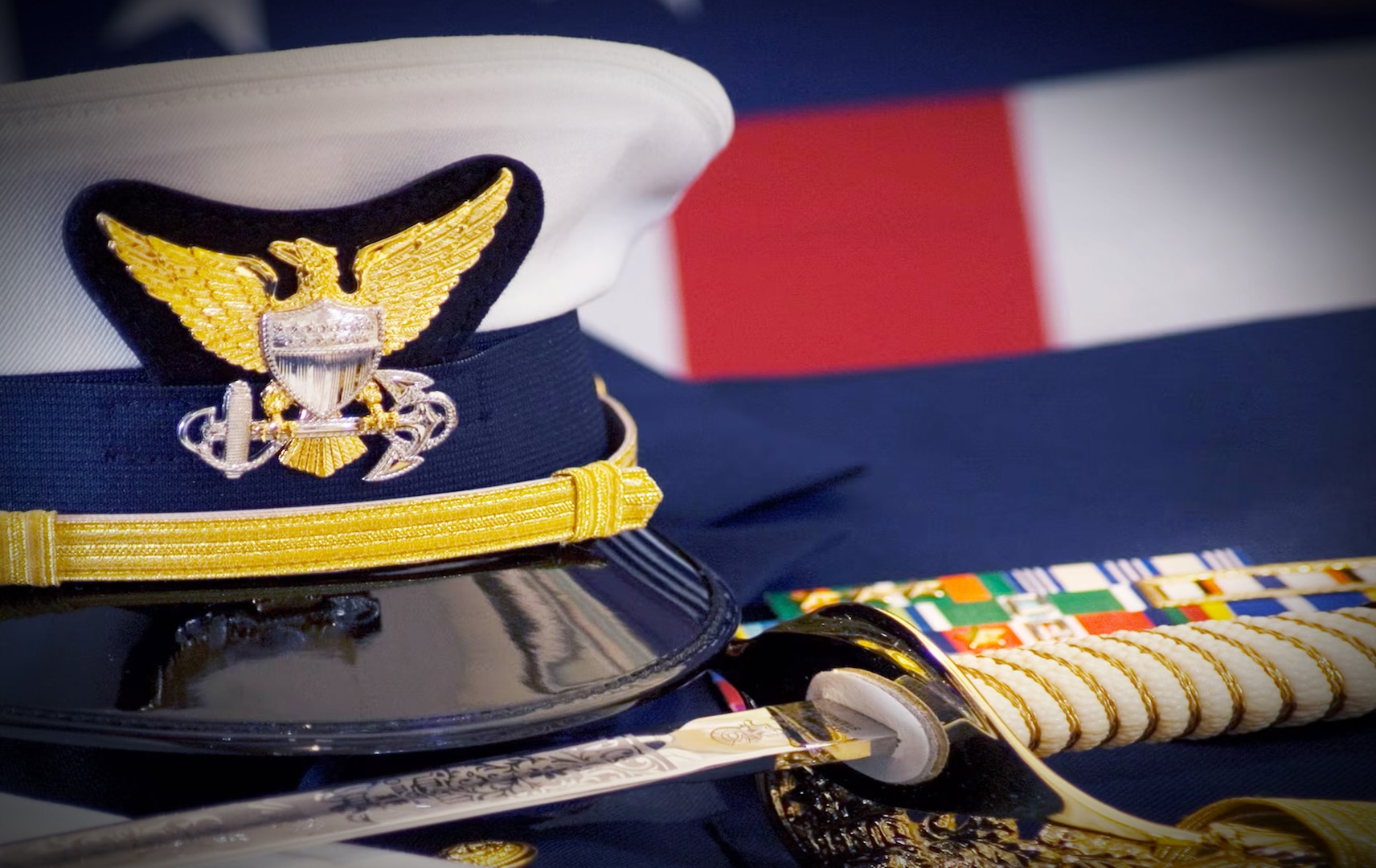 A Coast Guard Officer's hat, sword, gloves and ribbons are displayed together with the American Flag. (U.S. Coast Guard photo)