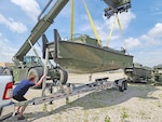 A man guides a boat onto a trailer.