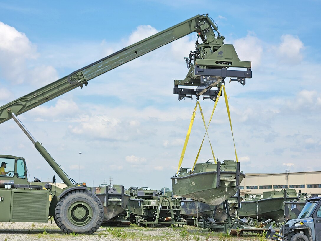 A large crane lowers a boat onto a trailer.